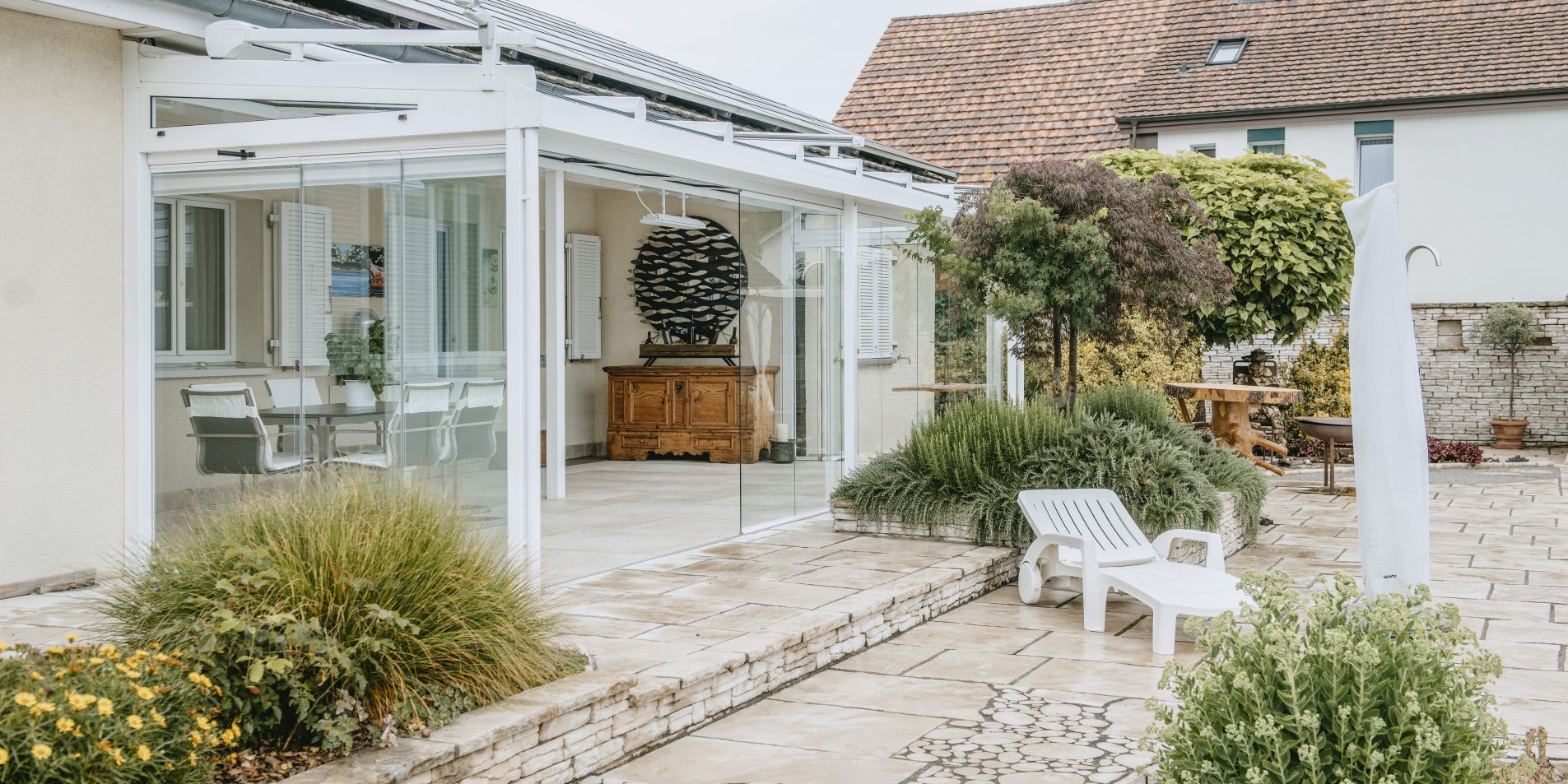 Weisser Sommergarten mit ROOFS Glasdach und COVER Terrassenverglasung in einem mediterranen Garten
