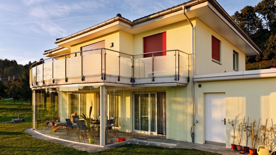 Einfamilienhaus im Abendlicht mit gerundeter COVER Terrassenverglasung unter dem Balkon