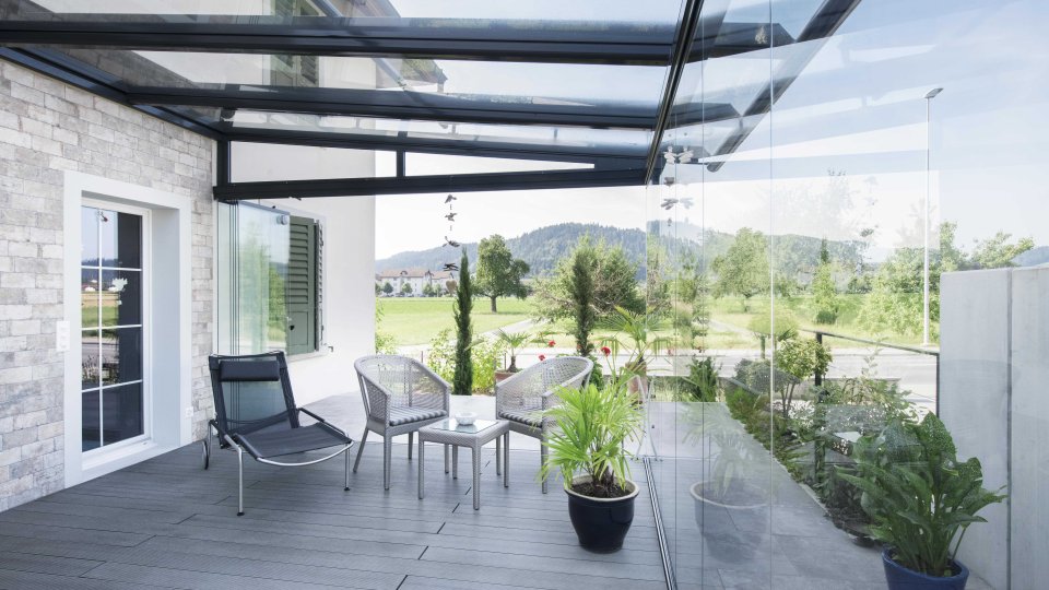 Sommergarten mit schwarzem Glasdach und COVER Verglasung, Liegestuhl, Sesseln und Topfpflanzen